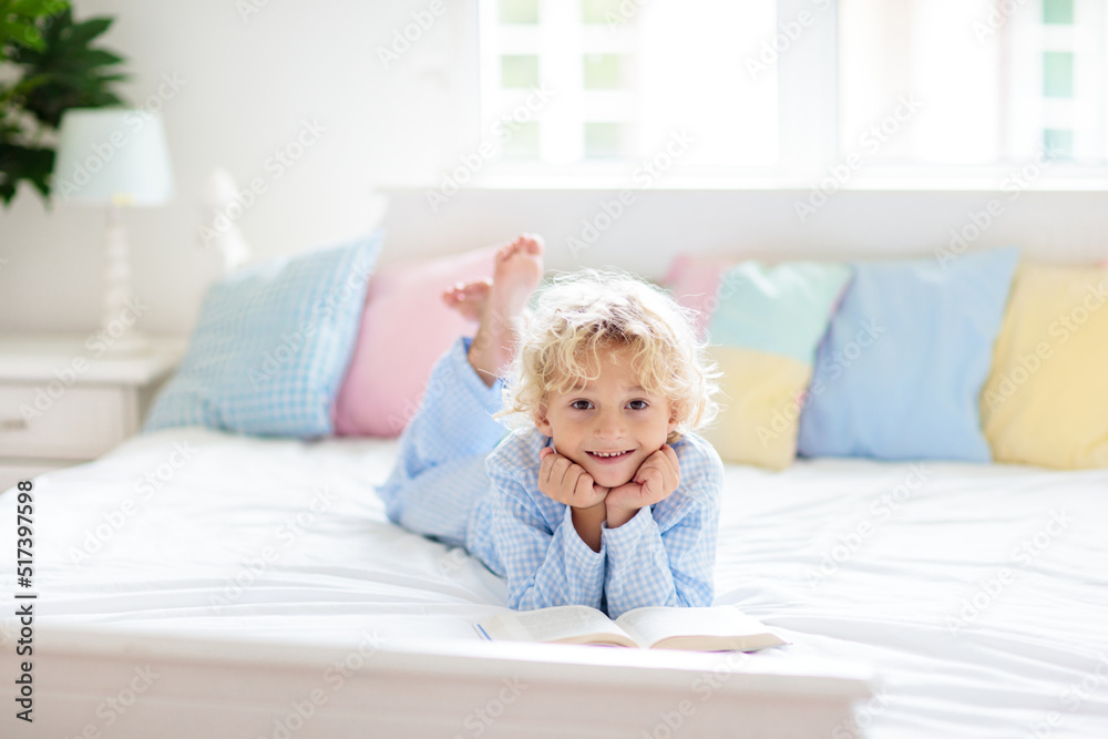 Wall mural child reading book in bed. kids read in bedroom.