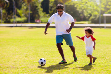 Father and son play football. Young active family.
