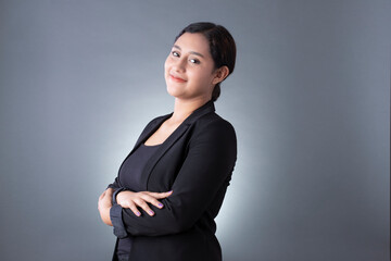 Mexican woman smiling with arms crossed with black blazer and gray background