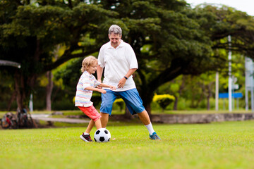 Obraz premium Father and son play football. Dad and kid run.