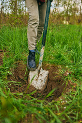 Female farmer digging ground in cloudy day. Woman working with shovel in field