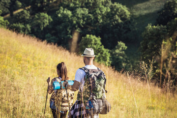 A happy couple climbs the hills in hiking gear.