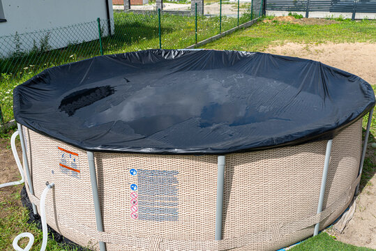 Large expansion pool with a diameter of 3.96 meters with black cover, set in the backyard next to the house.