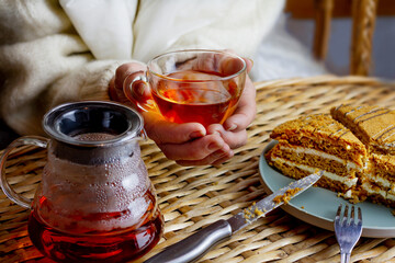 the old woman's hands are holding a transparent cup of tea