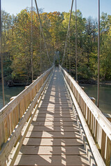 A wooden, walking, suspension bridge spans Sugar Creek in Turkey Run State park, Indiana.
