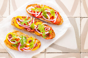 Healthy vegetarian toasts on parchment paper. Vegetarian sandwiches with fresh tomato, greens and olives. Vegetarian spanish tapas on til. Top view