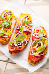 Healthy vegetarian toasts on parchment paper. Vegetarian sandwiches with fresh tomato, greens and olives. Vegetarian spanish tapas on til. Top view