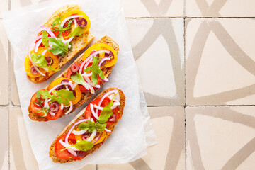 Healthy vegetarian toasts on parchment paper. Vegetarian sandwiches with fresh tomato, greens and olives. Vegetarian spanish tapas on til. Top view