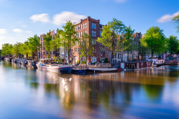 Obraz premium Amsterdam, Netherlands. View of houses and bridges. The famous Dutch canals and bridges. A cityscape at the day time. Travel photography.
