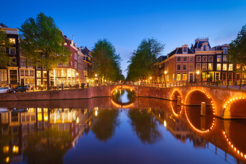 Fototapeta na wymiar Amsterdam, Netherlands. View of houses and bridges during sunset. The famous Dutch canals and bridges. A cityscape in the evening. Travel photography.