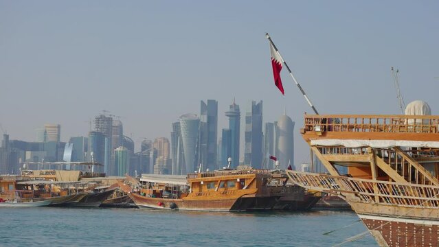 Doha skyline afternoon shot showing Dhows with Qatar flags in the Arabic gulf in foreground and Doha skyline in background
