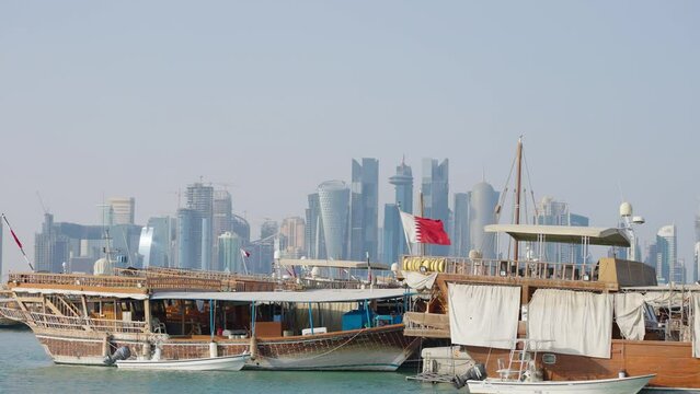 Doha skyline afternoon shot showing Dhows with Qatar flags in the Arabic gulf in foreground and Doha skyline in background
