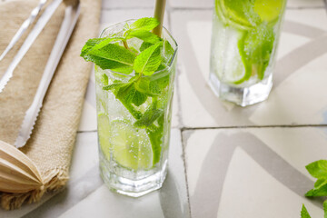 Mojito and bar accessories on a tile. Two glasses of mojito cocktail with mint and lime. Summer cocktail with bamboo straw