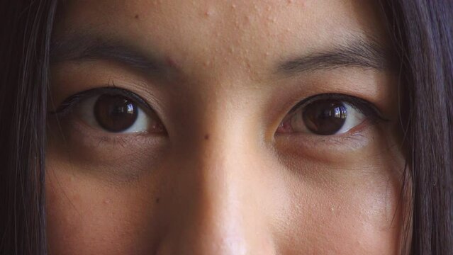 Portrait of a woman slowly opening her eyes while looking serious and deep in thought. Closeup on face of a female becoming conscious and aware of the world while perceiving and watching humanity