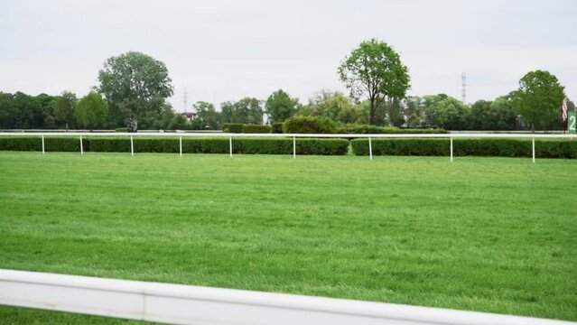 Many unrecognisable jockeys on horseback run to the finish line at the green racetrack hippodrome. Concept of competition speed.