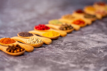 A set of spices on a gray background. Variety of spices from India. Food decoration design. Various spices, peppers and herbs close-up top view. Set of peppers, salt, herbs and spices for cooking.