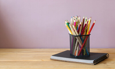 Colored pencils and a spiral notebook, stationery on the table.