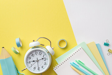 Back to school concept. Top view photo of school supplies alarm clock colorful notebooks pencil-case pens binder clips and adhesive tape on bicolor yellow and white background