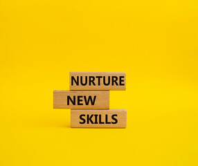 Nurture new skills symbol. Concept words Nurture new skills on wooden blocks. Beautiful yellow...