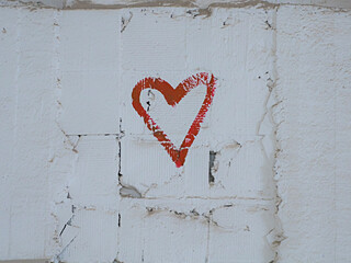 red paint drawing of a heart shape on the white brick wall background