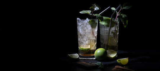 two moody drinks on a black background with mint and lime