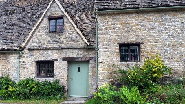 Wide angle shooting of the charming row of typical cotswold cottages in the historic village of Bibury, Gloucestershire. Fairy tale stone houses decorated with plants and flowers.