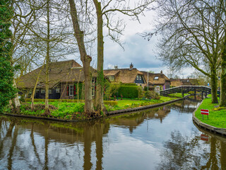 Fototapeta na wymiar Thatched roof houses on Canal side in the fairy tale village of Giethoorn, Netherlands