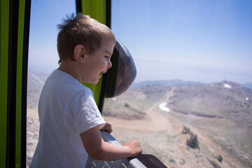 Little preschool boy in funicular cabin watching a mountain landscape