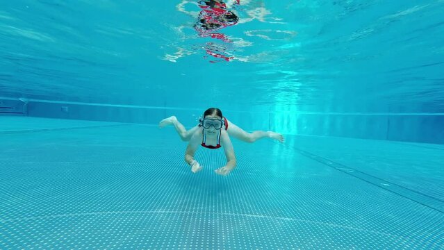 Little cute girl learning swimm under water in swimming pool at holidays