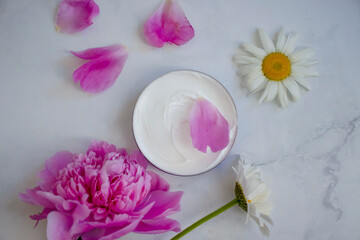 Obraz na płótnie Canvas Cosmetic cream, peony flower on a light background, chamomile flower