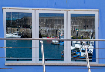 Reflections in the windows of some boats in the port of Lastres, Asturias, Spain