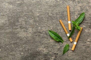 Menthol cigarettes and fresh mint leaves on colored background, Many cigarettes stacked together...