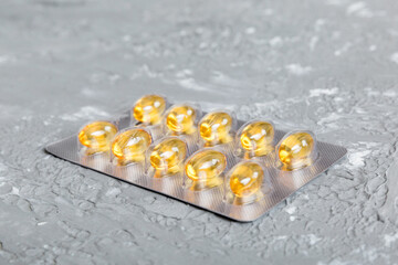 Blister package with fish oil capsules on color background. Medicine pills on a light background. Medicines and prescription pills flat lay background. Yellow medical tablets in blister