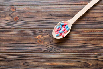 Vitamin capsules in a spoon on a colored background. Pills served as a healthy meal. Red soft gel vitamin supplement capsules on spoon
