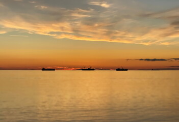 orange  gold sunset cloudy  sky at sea water reflection ship on horizon nature landscape seascape