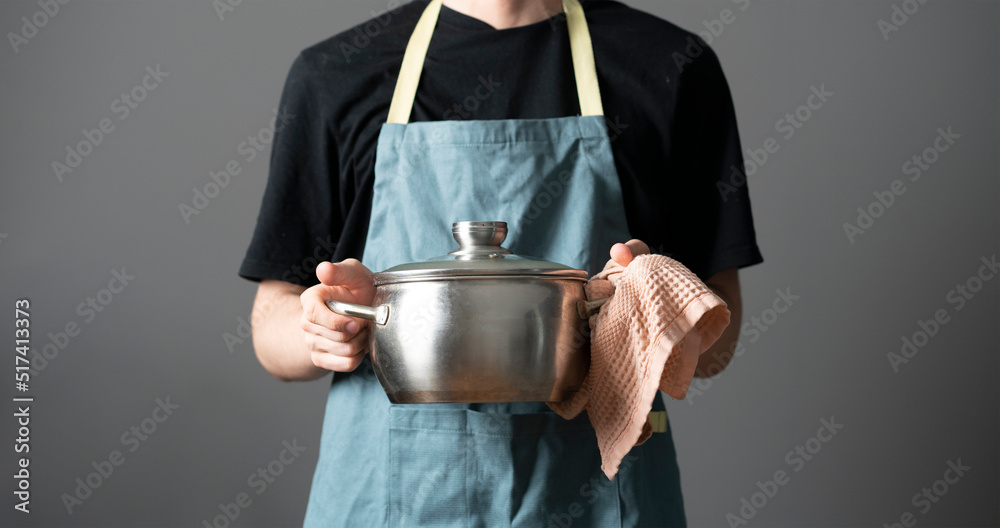 Wall mural chef in apron cooking dish holding a pot in the kitchen