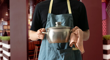 chef in apron cooking dish holding a pot in the kitchen