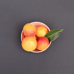 Orange aprocots in bowl against dark background. Minimal food concept. Flat lay.