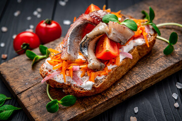 Sandwich with slices of pickled Atlantic herring fillet, pickled onions and carrots