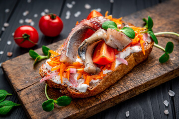 Sandwich with slices of pickled Atlantic herring fillet, pickled onions and carrots