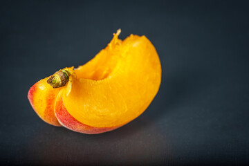 Ripe single apricot fruit slice cut open over dark background closeup