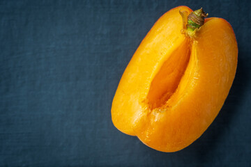 Ripe single apricot fruit slice cut open over dark background closeup