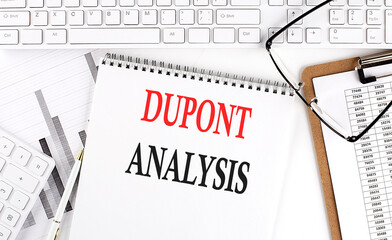 Text DuPont Analysis on Office desk table with keyboard, notepad and analysis chart on white background.