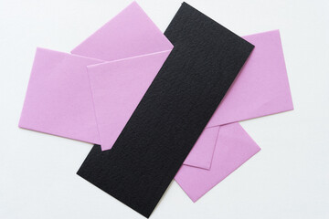 violet or pink paper tucked inside a black paper shape with a slit