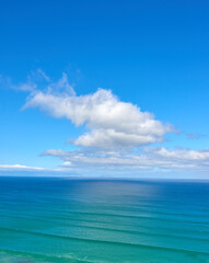 Beautiful cumulus clouds in a blue sky over a calm blue sea and ocean in summer. Gorgeous scenic view of the beach and blue water during the day. Idyllic and peaceful coastline for a summer vacation