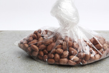 Peeled raw peanuts in a clear plastic bag on a gray table