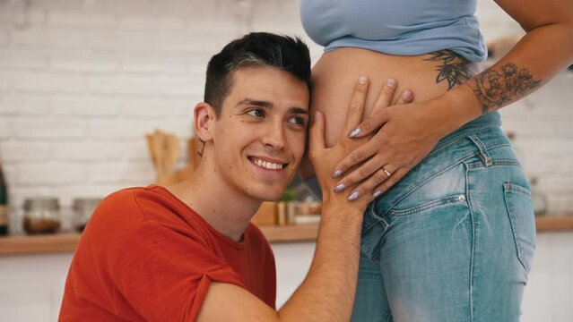 excited man listening to his baby in his pregnant wife's belly. High quality 4k footage
