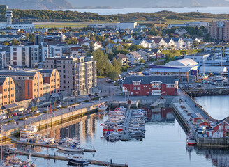 The landscape of the harbor in the city of Bodo on a summer day. A small port in an urban town with boats, buildings, and streets. Aerial view of a scenic location near mountain and nature