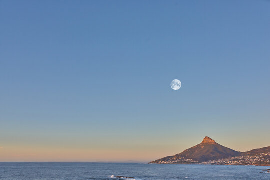Ocean landscape with a mountain on the coastline at sunset in South Africa. Scenic nature landscape of Lions Head at dawn near a calm peaceful sea against a blue horizon with copy space in Cape Town