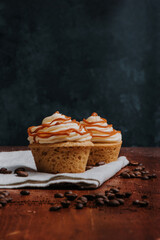 Cupcakes con frosting blanco y caramelo con fondo mesa de madera, deliciosos dulces de pastelería,...